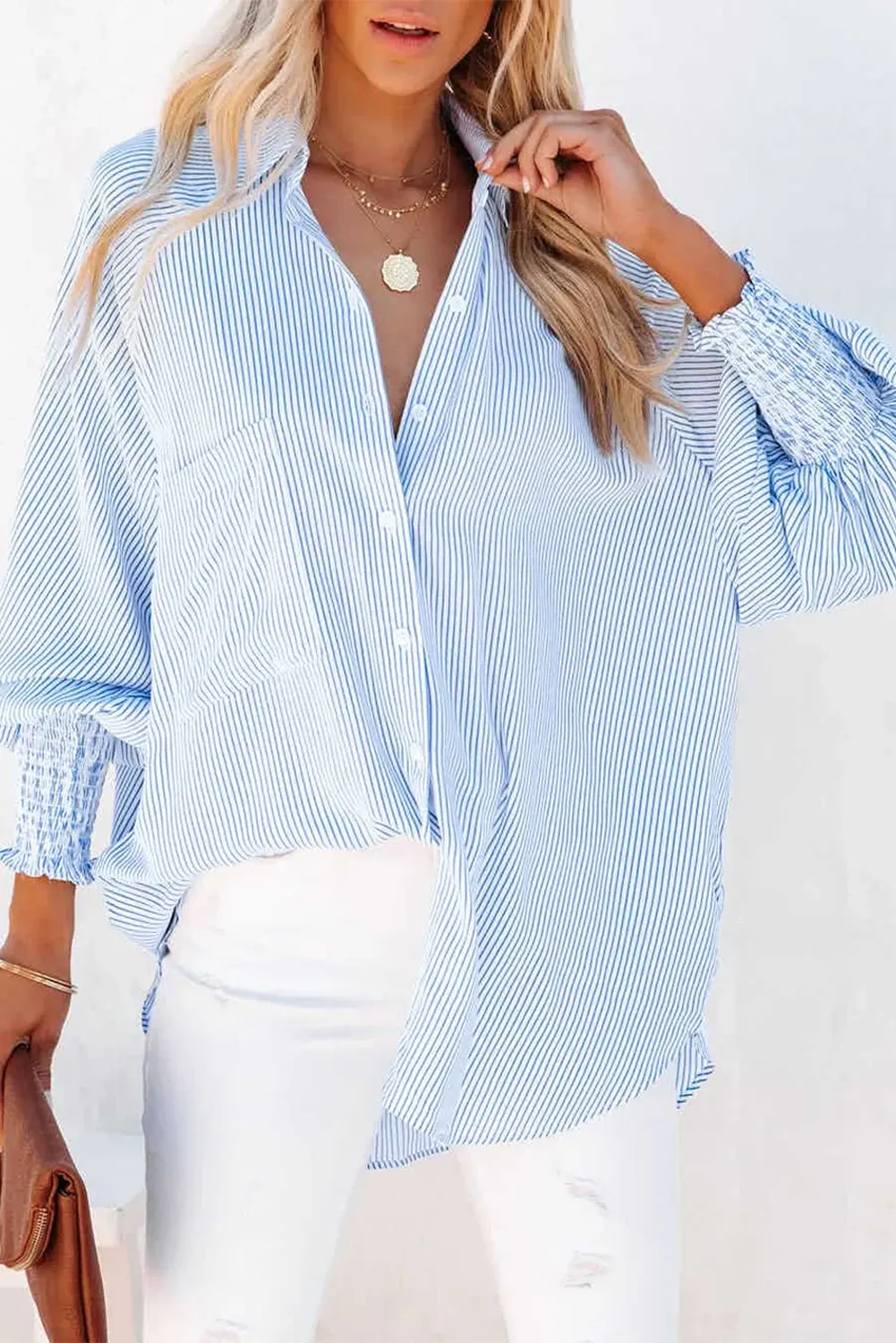 Woman wearing mid-length smocked shirt with striped lapel